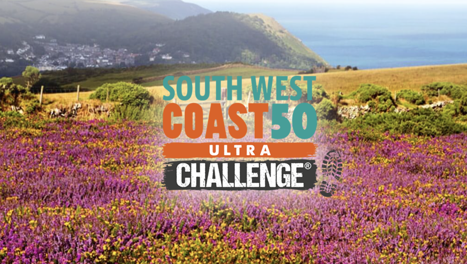 Vibrant coastal landscape along the South West Coast 50 route, featuring a field of purple and yellow wildflowers in the foreground, rolling hills, and the sea stretching into the horizon. A village nestles in the distance, adding to the scenic charm. The South West Coast 50 Ultra Challenge logo is prominently displayed over the image.