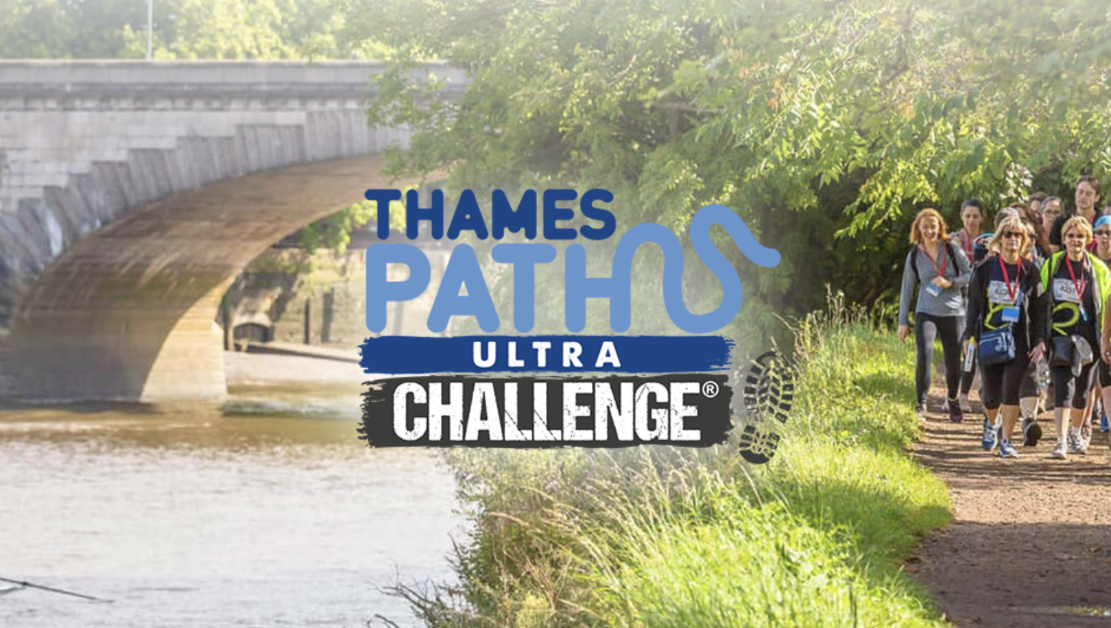 A group of participants walking along a scenic riverside trail during the Thames Path Ultra Challenge. The event logo, featuring the words "Thames Path Ultra Challenge" with a boot print design, is overlaid on the image. A historic stone bridge and lush greenery are visible in the background under bright sunlight.